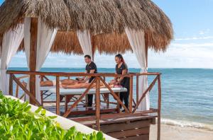 a man and woman sitting on a bed on the beach at Desire Riviera Maya Resort All Inclusive - Couples Only in Puerto Morelos