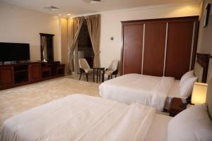 a hotel room with two beds and a flat screen tv at فندق هلا اثنين in Arar