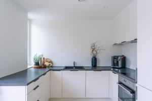 a kitchen with white cabinets and a black counter top at Modern Villas in Plush town in Tromsø