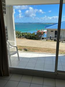 a window with a chair looking out at the ocean at Suite Résidence Mont Vernon in Orient Bay French St Martin