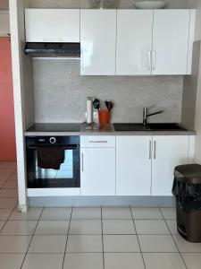 a kitchen with white cabinets and a sink and a stove at Suite Résidence Mont Vernon in Orient Bay French St Martin