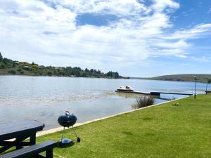 ein Grill auf einem Picknicktisch neben einem See in der Unterkunft LAKE-HOUSE CABIN in Witbank