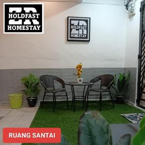 un patio con mesa y sillas sobre hierba en ZR HOLDFAST HOMESTAY BUKIT KATIL MELAKA, en Kampong Bukit Beruang