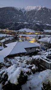 uma casa coberta de neve com montanhas ao fundo em Landhaus Appartment em Pettnau