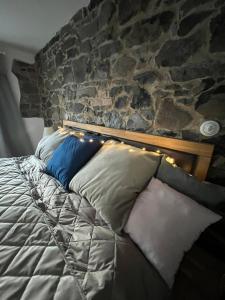 a bed with pillows and a stone wall at ŠTAJNHAUS DUBICE 