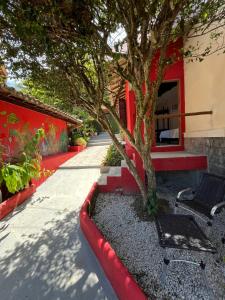 a tree and a bench next to a building at Novos Baianos Hostel e Pousada in Arraial d'Ajuda