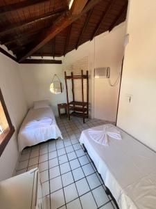 a room with two beds and a chair in it at Novos Baianos Hostel e Pousada in Arraial d'Ajuda