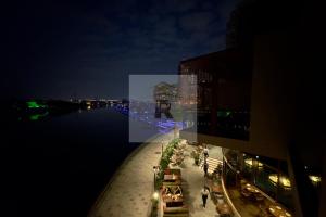 Palm View East Jumeira - Studio Apartment في دبي: اطلالة على نهر في الليل مع مبنى