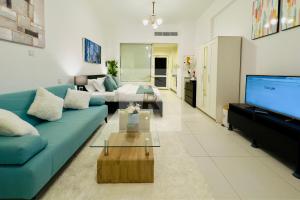 Palm View East Jumeira - Studio Apartment في دبي: غرفة معيشة مع أريكة زرقاء وتلفزيون