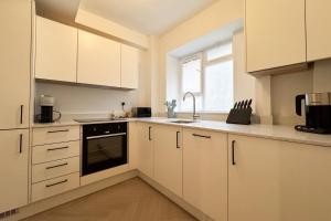 a kitchen with white cabinets and a sink and a window at Be London - Farringdon Apartments in London