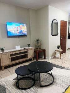 a living room with a table and a tv on the wall at Exclusive Stays @ Rea's Oceanic Hotels in Durban