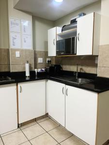 a kitchen with white cabinets and a microwave at Exclusive Stays @ Rea's Oceanic Hotels in Durban