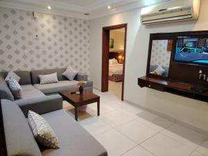 a living room with a couch and a flat screen tv at العالية للشقق المفروشه الشهري in Jeddah
