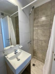 y baño blanco con lavabo y ducha. en Rent a Flat Nueva Cordoba en Córdoba
