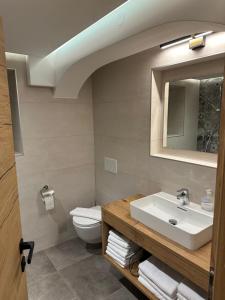 łazienka z umywalką, toaletą i lustrem w obiekcie Ferienwohnung Krallinger w mieście Wenns