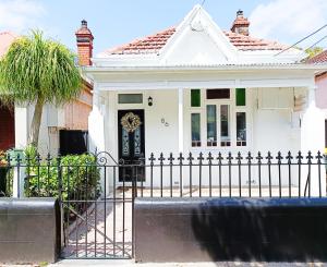 a white house with a wrought iron fence at Stunning Queen Room 1Min Walk to Station with 55 Inch TV in Sydney