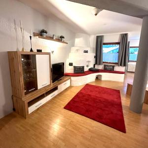 a living room with a television and a red rug at Landhaus Solaris in Leutasch