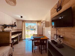 a kitchen with a table and a tv on the wall at Vila Madu in Bombinhas