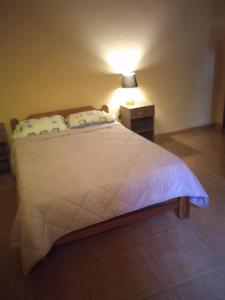 1 dormitorio con 1 cama blanca grande con lámpara en El Lodge, en Santa María