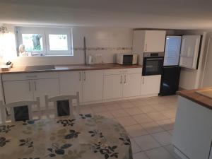 a kitchen with white cabinets and a black refrigerator at SUB ROSA Two-Bedroom Apartment in Balatonfenyves