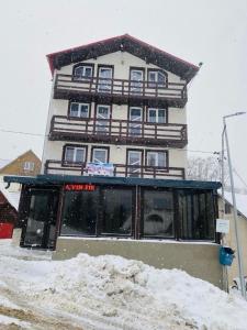 een hoog gebouw in de sneeuw voor de deur bij Pensiunea White House in Straja
