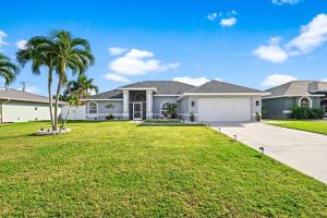 uma grande casa branca com palmeiras no quintal em Bohemian Cape Bungalow em Cape Coral