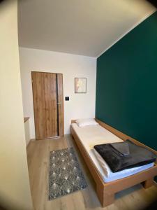een slaapkamer met een bed met een groene muur en een deur bij HOTEL MILO - Noclegi Bartoszyce in Bartoszyce
