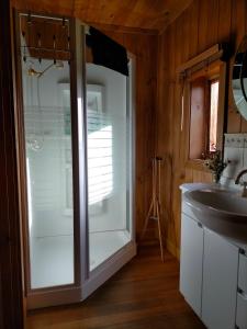 a bathroom with a glass refrigerator next to a sink at Hideaway Farmlet Romantic Cottage with Miniature Goats in Penguin