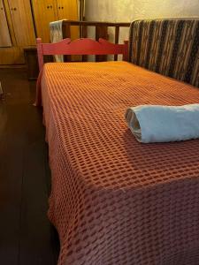 a bed with an orange blanket on top of it at Selena Rooms in Agia Galini