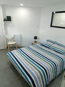 a bed with a striped comforter in a bedroom at Appartement dans maison atypique in Montrond-les-Bains