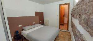 - une chambre avec un lit et un mur en pierre dans l'établissement Da Bruschi Appartamento Assisi, à Assise