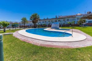 a swimming pool in a park with a building in the background at Casa grande , piscina y garaje in Aljaraque
