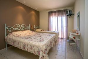 a bedroom with two beds and a tv and a window at Studios Akrogiali in Limenaria