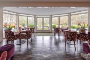 a restaurant with tables and chairs and windows at Landgoed de Rosep in Oisterwijk