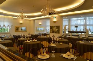 un ristorante con tavoli e sedie neri e un pianoforte di Hotel Europa Milano Marittima a Milano Marittima