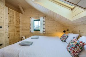 a bedroom with a white bed in a wooden room at Apartamenty Dubacik in Tylicz