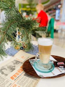 a glass of coffee sitting on a plate next to a christmas tree at HOTEL MILO - Noclegi Bartoszyce in Bartoszyce