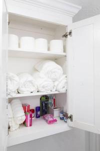 a white cabinet filled with towels and toilet paper at Home in Hempstead in Hempstead