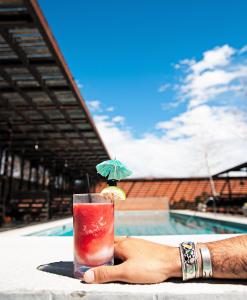 a person holding a drink on a table next to a pool at Hotel Saint George in Marfa