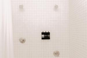 W wyłożonej białymi kafelkami łazience znajdują się 2 gałki na ścianie. w obiekcie Hotel Saint George w mieście Marfa