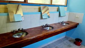 twee wastafels in een openbare badkamer met twee spiegels bij Hostel,Dormis y Camping Costa Bolsón in El Bolsón