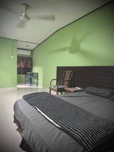 una camera con un grande letto e una sedia di Junest Hut a Pantai Cenang