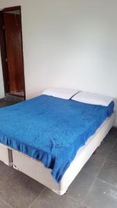 Una cama con una manta azul encima. en Hostel família Campineira en Campinas