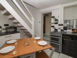 eine Küche mit einem Holztisch und einer Treppe in der Unterkunft Quarry Cottage in Buxton