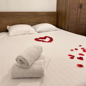 ein Bett mit roten Rosen und Handtüchern darauf in der Unterkunft Bonvillas Brezovicë riverside apartments in Brezovica