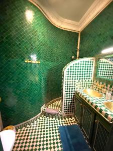 een groene betegelde badkamer met een wastafel en een spiegel bij Riad La Perle Rouge in Marrakesh