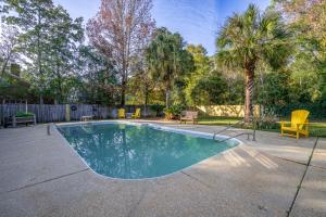 a swimming pool in a yard with chairs and trees at Yellow Adirondack Hideaway in Gulfport