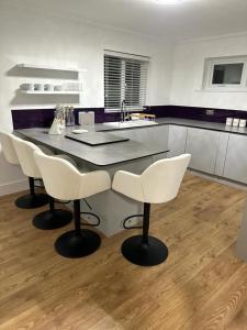 een keuken met een tafel en 2 witte stoelen bij Seahaven in Sandbanks in Poole