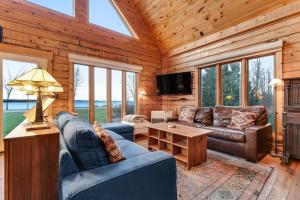 a living room with couches and a television in a log cabin at Sunset Hideaway in Isle la Motte