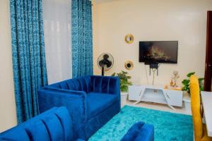 a living room with a blue couch and a tv at Belch Apartment in Kisumu